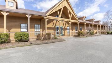 A row of log cabin-style buildings with a covered front porch and a central entrance.