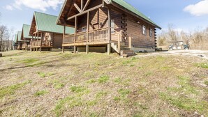 Eine Blockhütte mit Veranda und einem grünen Dach.