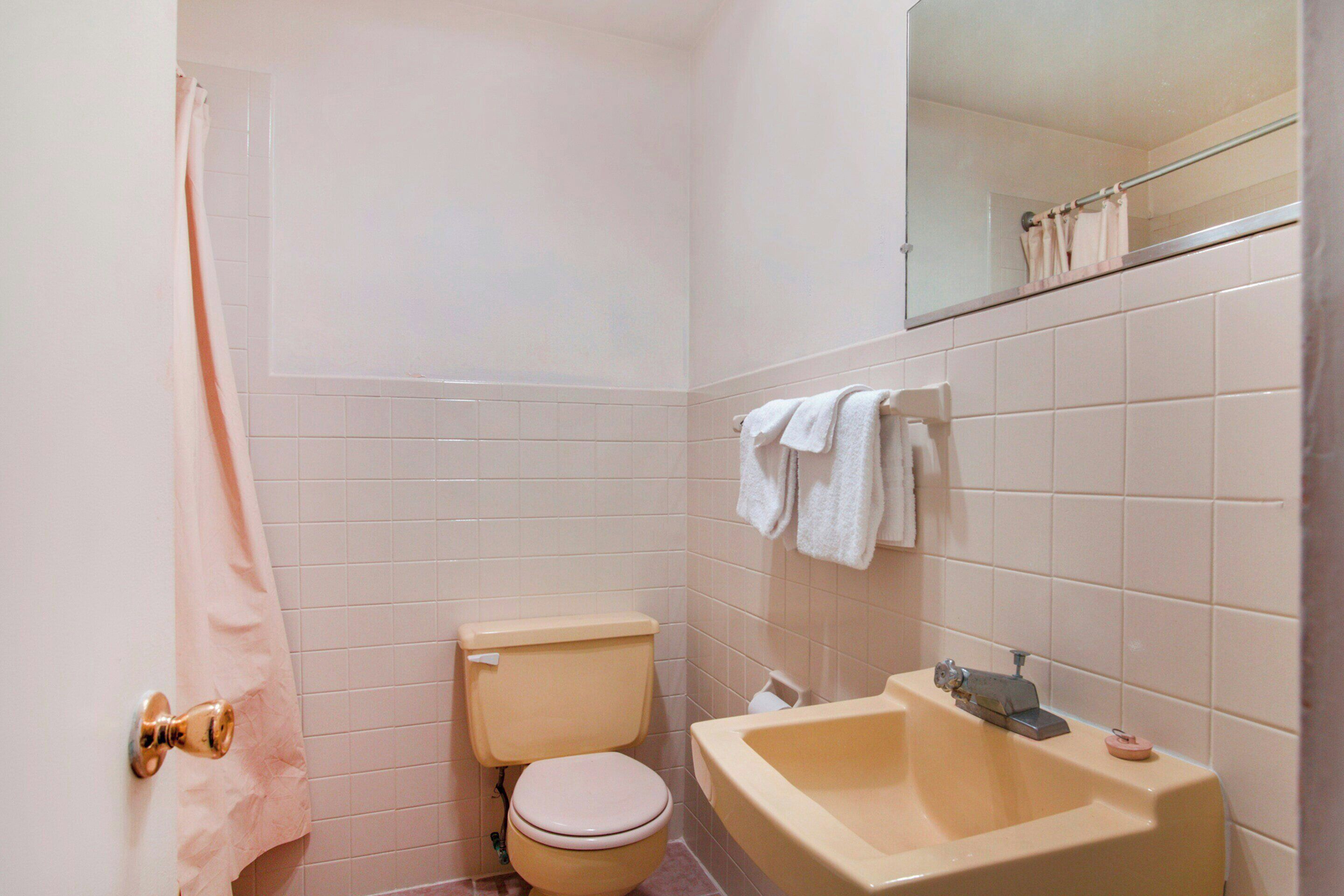 A small bathroom with a toilet, sink, and a mirror above the sink.