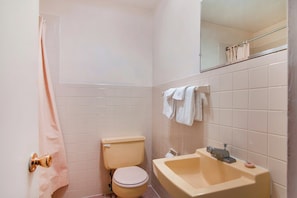 Un baño pequeño con inodoro, lavamanos y espejo sobre él.