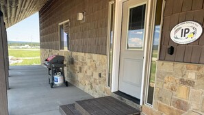 Un porche abrité avec un mur en pierre, une porte en bois et un chariot pour barbecue.