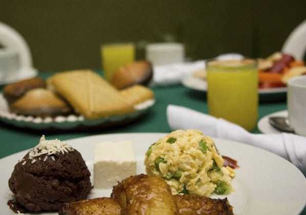 A breakfast plate with chocolate dessert, scrambled eggs, and toast.
