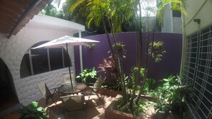 A patio with a table and chairs, surrounded by potted plants and a purple wall. - Hotel El Torogoz (San Salvador)