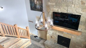 Una sala de estar con chimenea de piedra, televisor montado y banco de madera.