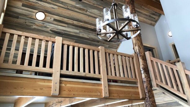 Interior de madera con techo inclinado, ventilador de techo y lámpara colgante.