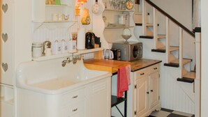 Una cocina con un lavamanos, armarios, una estufa y un reloj en la pared.