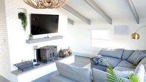 Una sala de estar moderna con chimenea, un televisor de pantalla plana grande y un sofá gris.
