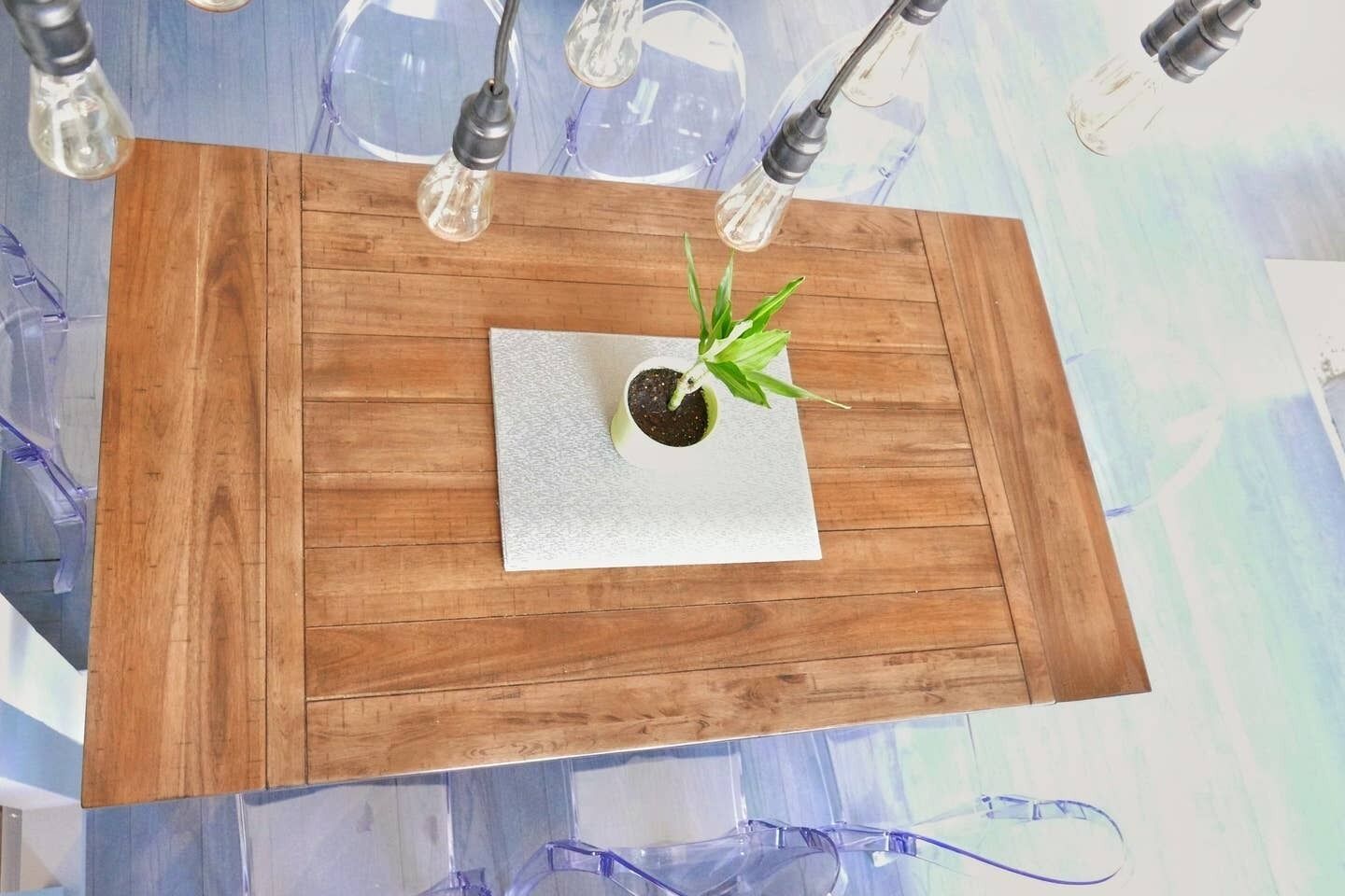 Uma mesa de madeira com uma planta em vaso sobre uma superfície branca texturizada.