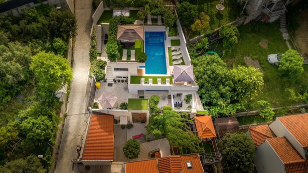 Oversigtsbillede af en bolig med swimmingpool, flere altaner og grøn bevoksning omkring.