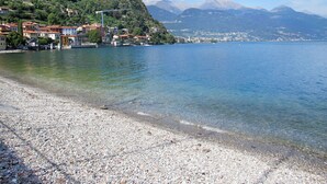 A pebble beach with buildings on a hillside and mountains in the background. - Lovely apartment for 5 guests with A/C, WIFI and balcony (Musso)