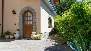 A building with a stone facade, a wooden door, and a balcony with metal railings. - Beautiful apartment for 5 people with hot tub, WIFI, TV, terrace and pets allowed (Colico)