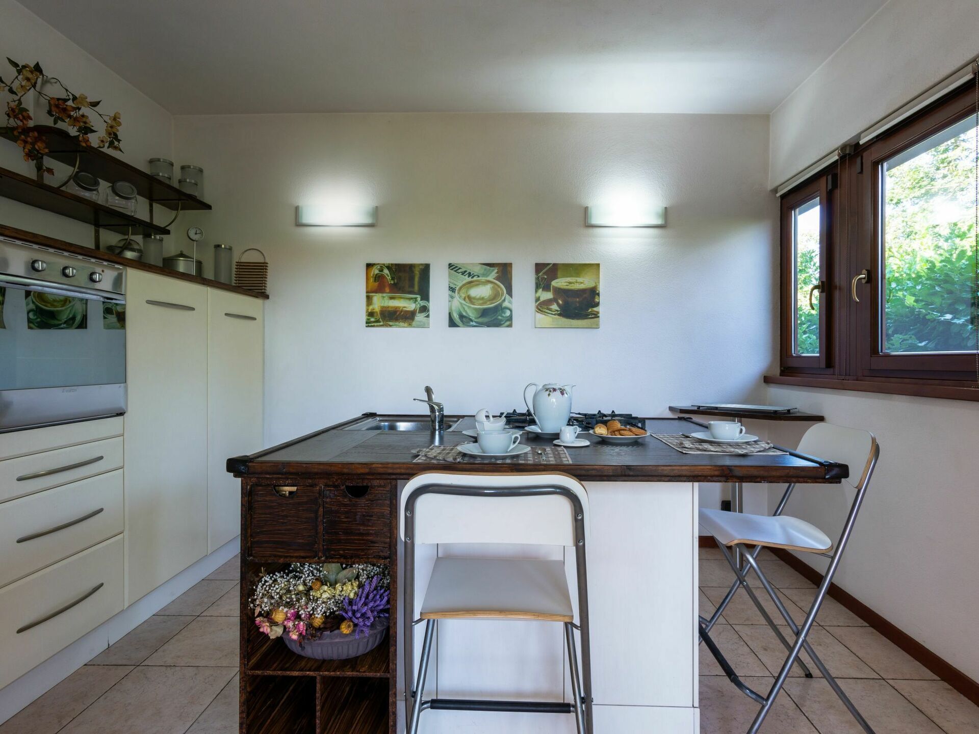 A kitchen with a central island, a built-in oven, a sink, and a window with a view of greenery.