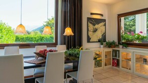 Comedor con mesa, sillas y vistas a la vegetación a través de amplios ventanales.