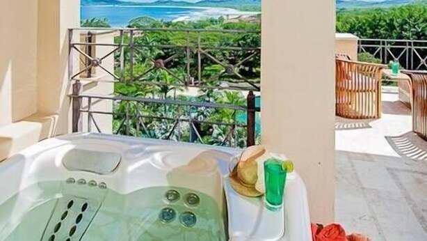 Un bain à remous sur un balcon offrant une vue sur un paysage montagneux.