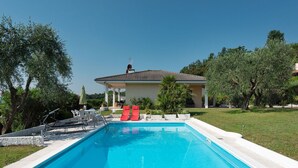 Piscina con sillas de descanso y un patio techado.