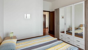 Un dormitorio con cama, armario y mesita de noche.
