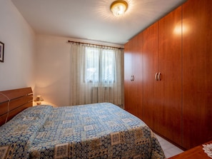 A bedroom with a bed, wooden wardrobe, and a window with curtains. - Cosy apartment for 5 guests with WIFI, TV and pets allowed (Molini)