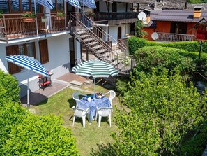 Un patio con mesa y sillas, una escalera y un balcón con barandilla.