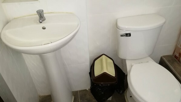 Uma casa de banho com uma sanita e uma pia brancas.