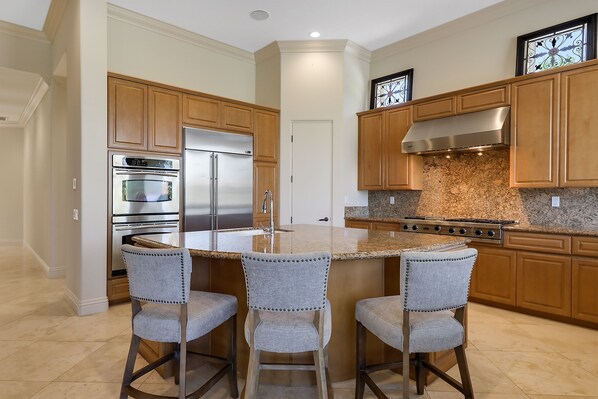 A modern kitchen with wooden cabinets, stainless steel appliances, and a granite countertop.