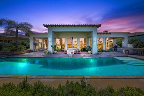 A poolside area with a covered patio, outdoor furniture, and a clear view of the pool.