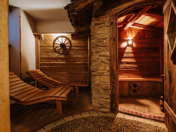 A rustic wooden cabin with a stone wall, a wooden bench, and a wooden wheel.