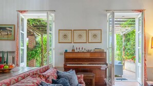 Una sala de estar con un piano, un sofá y una mesa de comedor con fruta.