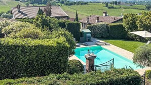Propiedad residencial con piscina, rodeada de setos cuidados y vistas a viñedos.