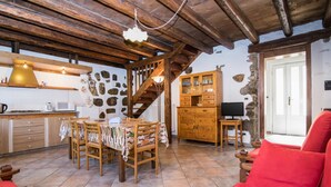 Eine rustikale Küche mit Holzbalken, einer Steinwand und einem Essbereich mit Tisch und Stühlen.