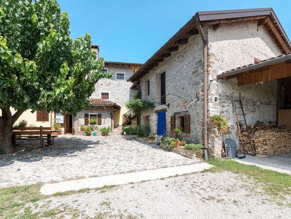 Un patio empedrado con edificios de piedra, un banco de madera y un árbol.