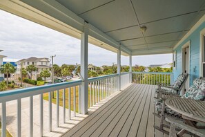 A covered porch with a railing, a table, and chairs.