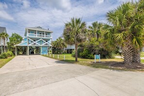 A two-story building with a balcony, surrounded by palm trees and a concrete pathway.