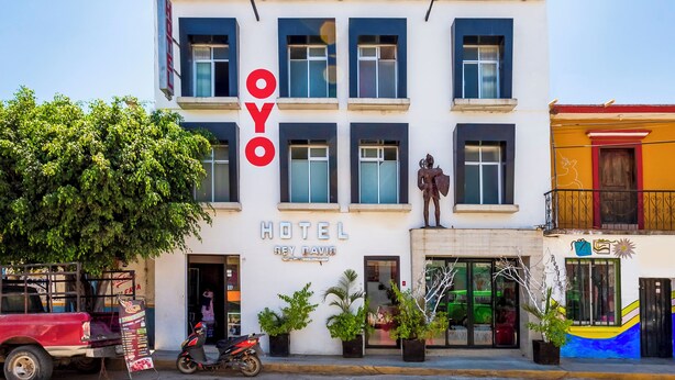 A hotel named "OYO" with a modern facade, large windows, and a statue on the ground floor.