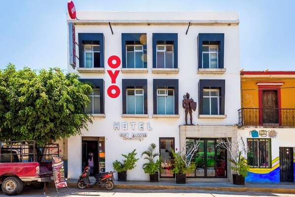 A hotel named "OYO" with a modern facade, large windows, and a statue on the ground floor.