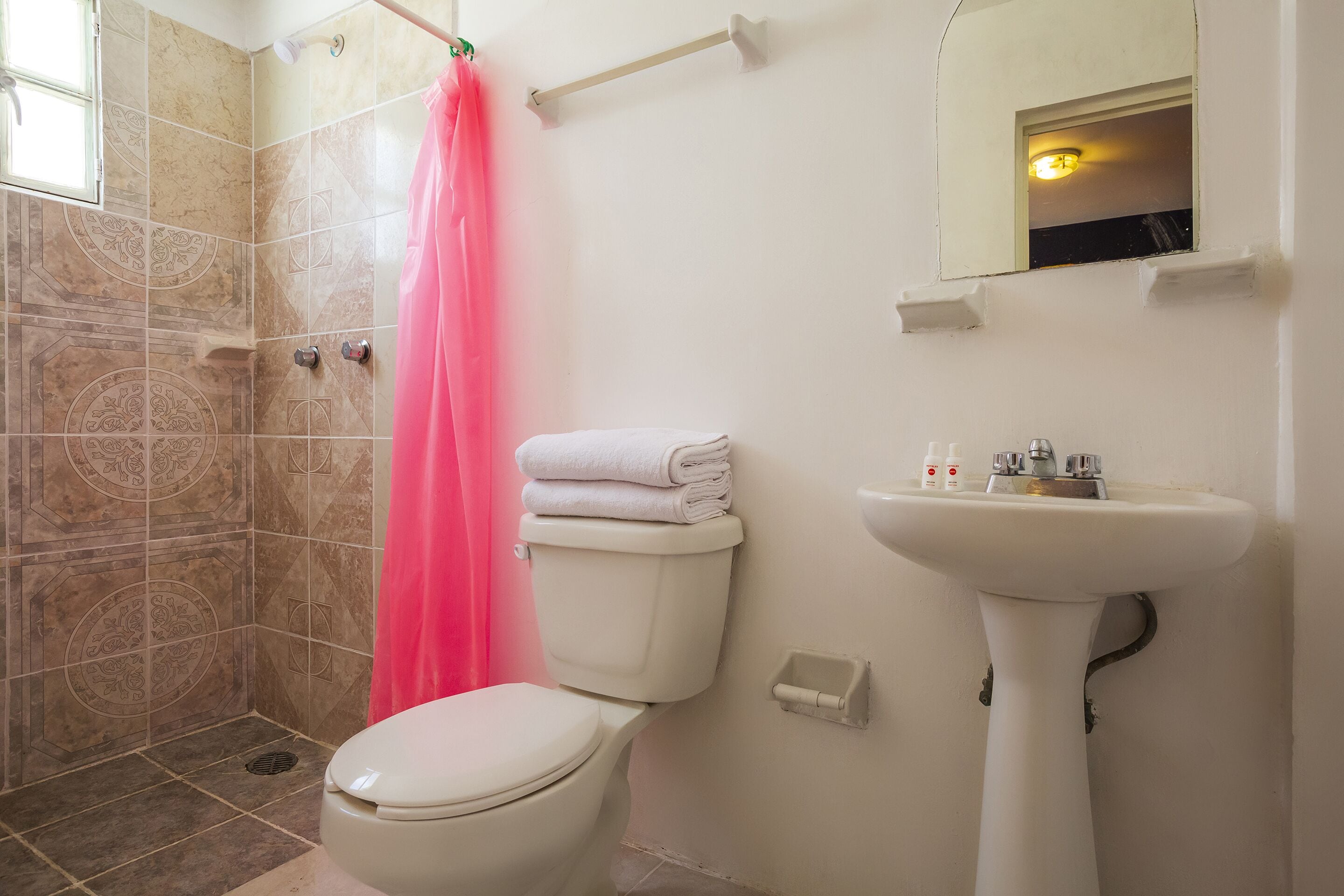 Un baño con inodoro, lavamanos y zona de ducha.
