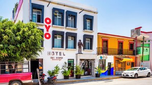 A hotel with a white facade, multiple windows, and a statue on the front.