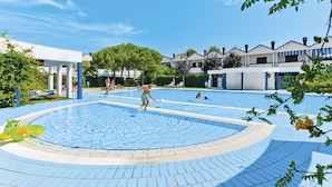 Une piscine dotée d’une plage carrelée, entourée de bâtiments présentant un style architectural uniforme.