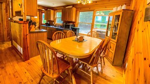 A wooden cabin-style kitchen with a dining table and chairs, a microwave, and a refrigerator.