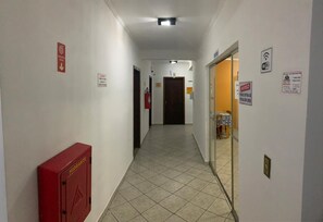 A hallway with a fire extinguisher, a water fountain, and a WiFi sign. - Pousada Martin de Sá (Caraguatatuba)