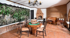 Una habitación con mesa de billar, sillas, chimenea y pared de ladrillo.