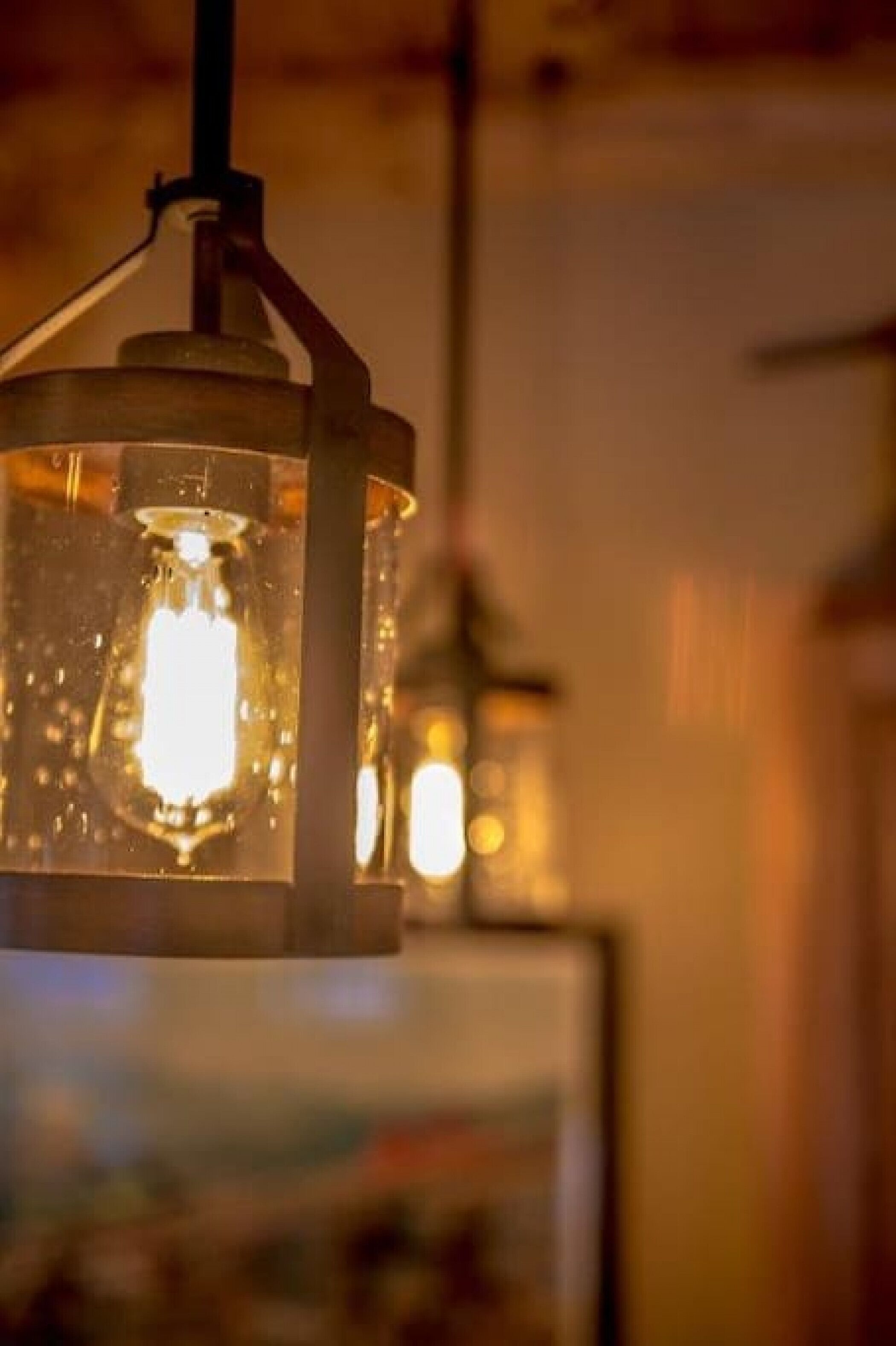 A close-up of a vintage-style hanging light fixture with a visible filament bulb.