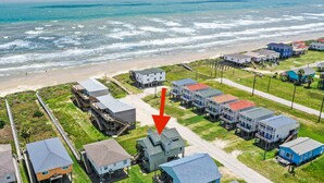 Vista aérea de una zona residencial costera con casas, una playa y un muelle.