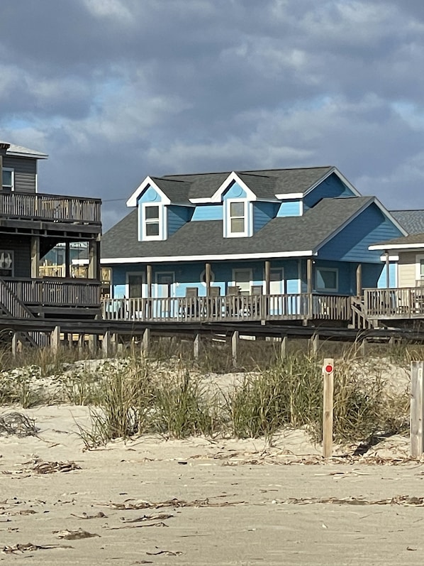 Una casa frente a la playa con un deck de madera y un balcón.