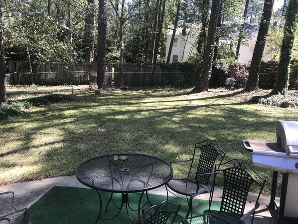 Enjoy al fresco dining and relaxation in this serene backyard patio, complete with a barbecue grill and comfortable seating for four.