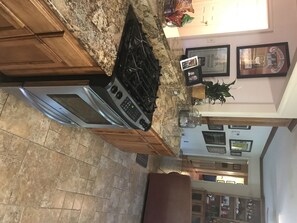 Kitchen features a stove, oven, and cabinetry, with a potted plant and framed pictures on the wall.
