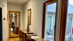 Una cocina moderna con suelo de madera, una zona de comedor con mesa de cristal y un amplio ventanal corredero que da a un patio exterior.