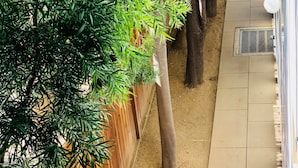 Un estrecho pasillo exterior con una valla de madera a un lado y un camino de baldosas al otro.