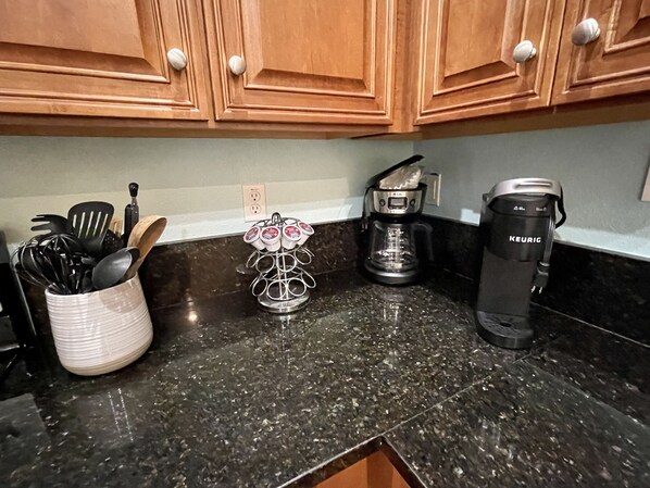 A kitchen counter with a coffee maker, a mug holder, and a utensil holder.