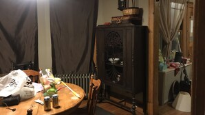 Un comedor con una mesa de madera, sillas, un armario con un reloj y un radiador.