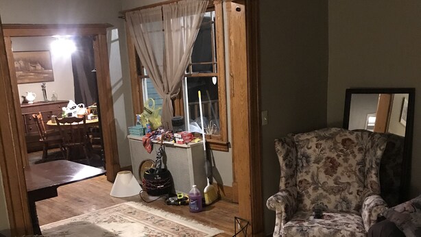 Una sala de estar con un sillón floral, una mesa de centro de madera y un comedor con mesa y sillas.